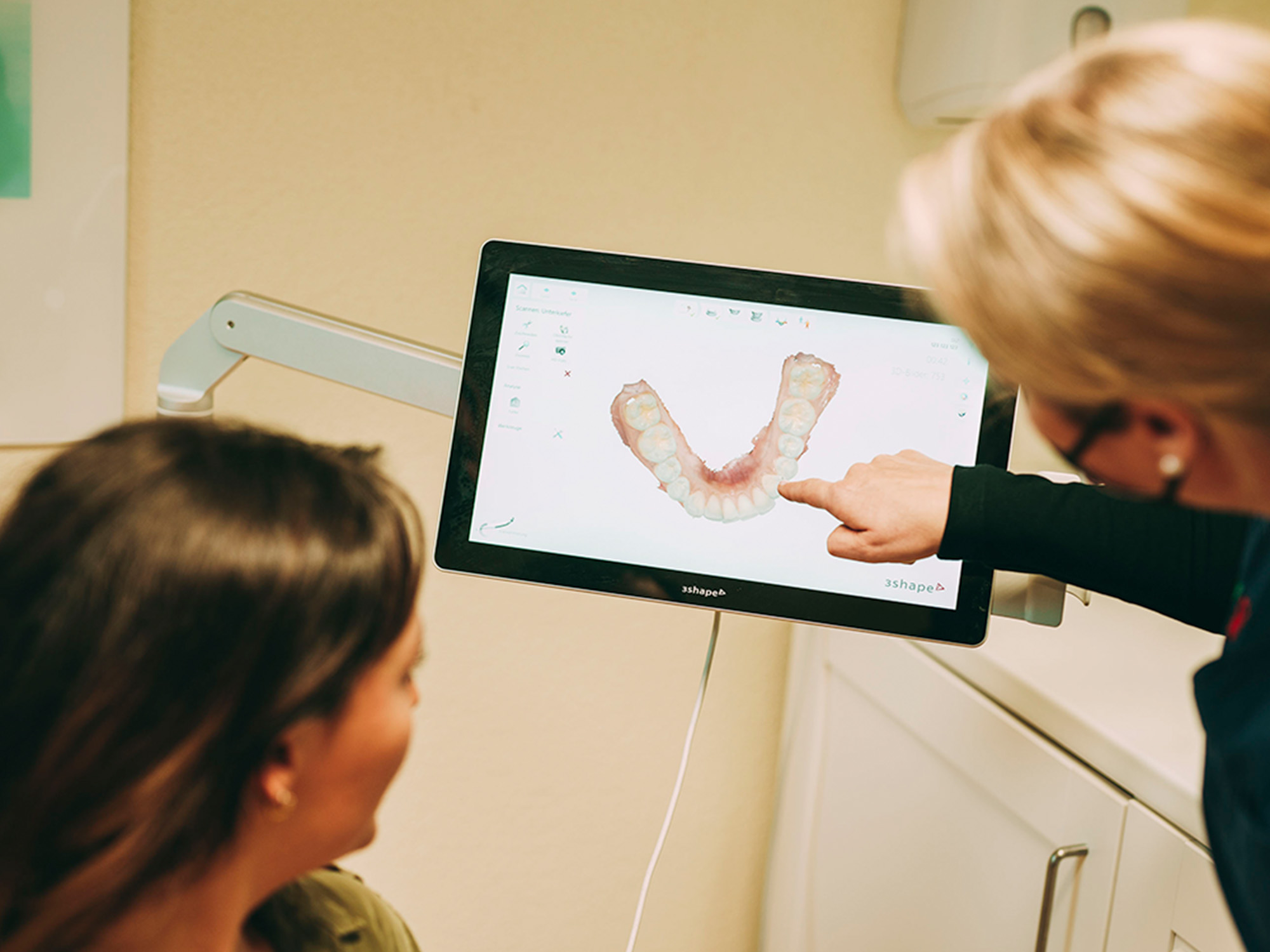 Dr. Bareis zeigt der Patientin den digitalen Abdruck ihrer Zähne auf dem Bildschirm.